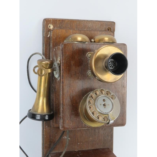 69 - A vintage oak wall mounted brass and bakelite telephone, early 20th century. 45.5 cm height. 
Condit... 