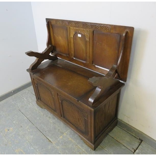 737 - A reproduction oak monk’s bench, the panelled back with lunette carved frieze, above a box settle ba... 