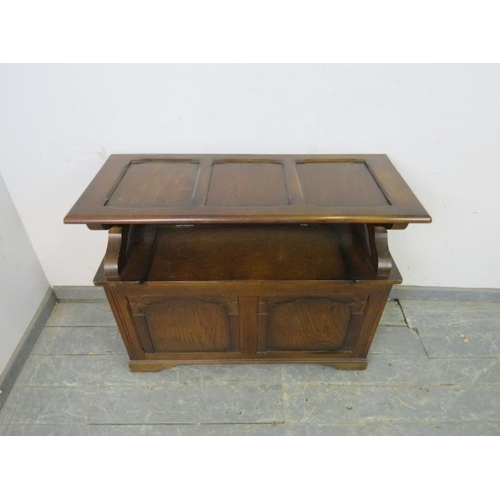 737 - A reproduction oak monk’s bench, the panelled back with lunette carved frieze, above a box settle ba... 