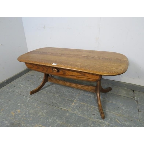 751 - A vintage elm rectangular coffee table in the manner of Ercol, having one lone frieze drawer, on cur... 