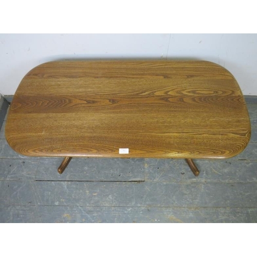 751 - A vintage elm rectangular coffee table in the manner of Ercol, having one lone frieze drawer, on cur... 