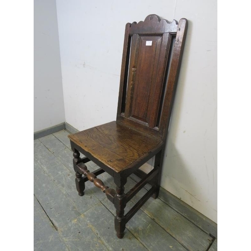 767 - An early 18th century oak hall chair, the backrest with shaped cornice and fielded central panel, on... 