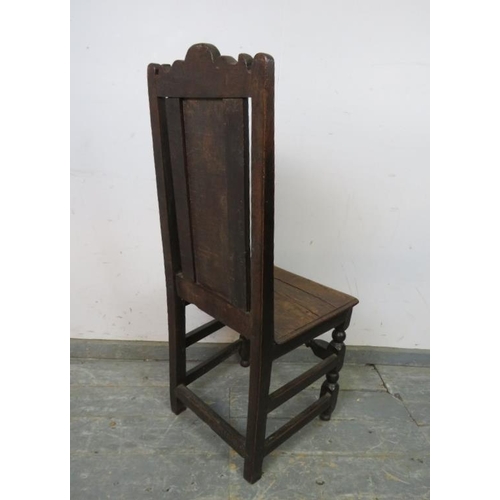 767 - An early 18th century oak hall chair, the backrest with shaped cornice and fielded central panel, on... 