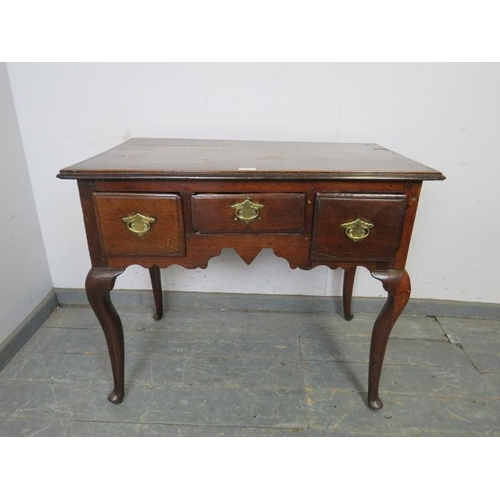 780 - An early 18th century oak lowboy, housing three short drawers with brass handles, above a shaped apr... 