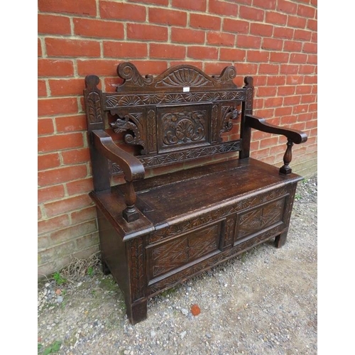 822 - An antique oak settle in the 17th century taste, the relief carved and shaped back joined to a box s... 