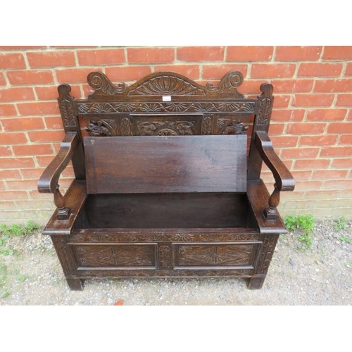 822 - An antique oak settle in the 17th century taste, the relief carved and shaped back joined to a box s... 