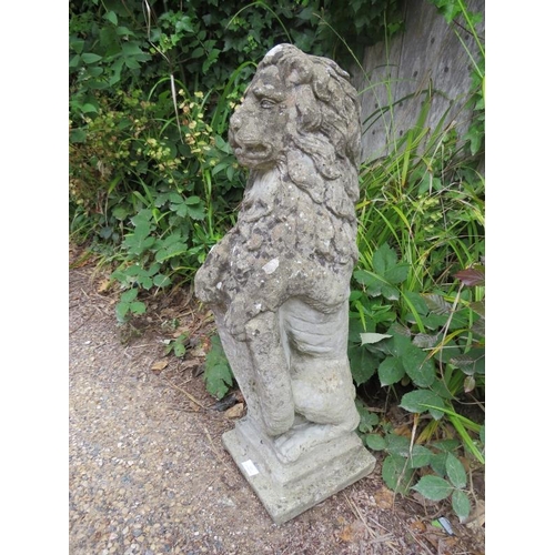 824 - A weathered reconstituted stone lion couchant, with heraldic shield, on a plinth base. 
H81cm W24cm ... 