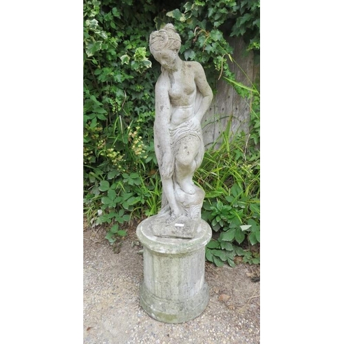 832 - A weathered reconstituted stone garden statue modelled as a Classical maiden on a reeded column plin... 