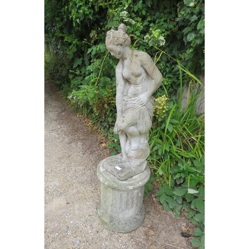 832 - A weathered reconstituted stone garden statue modelled as a Classical maiden on a reeded column plin... 