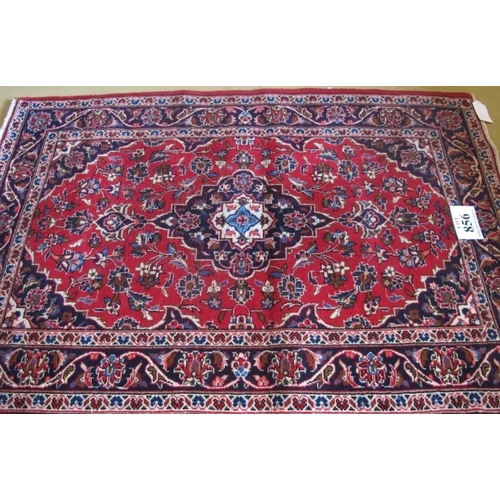 856 - A Persian Kashan rug.  Central pattern on blue foliage on a red ground. 150cm x 100cm (approx) Condi... 