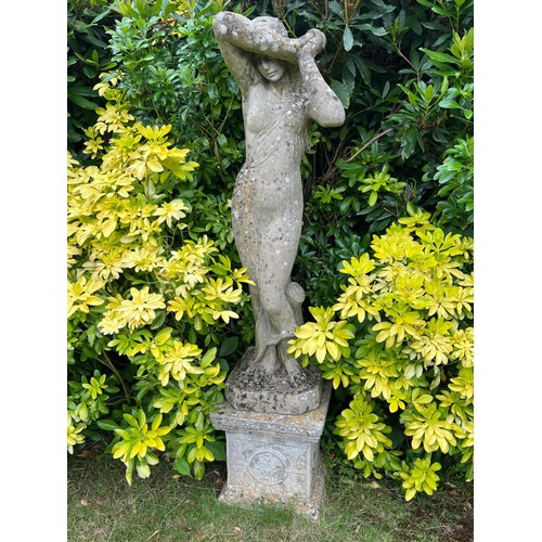 836 - A large weathered reconstituted stone garden statue modelled as a Classical maiden, on a square plin... 