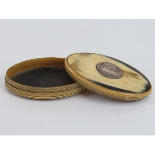 193 - A late Georgian carved horn snuff box. Of elliptical form, the cover mounted with a white metal plaq... 