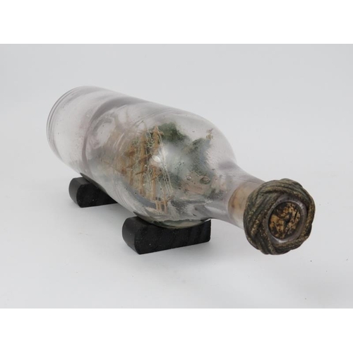 253 - An antique ship in a bottle modelled with a clipper sailing ship and tug in a coastal setting. 30.7 ... 