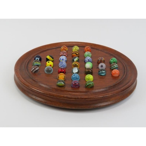 4 - A turned oak Solitaire board with glass marbles, late 19th/early 20th century. Board: 25 cm diameter... 