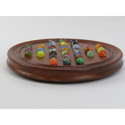 4 - A turned oak Solitaire board with glass marbles, late 19th/early 20th century. Board: 25 cm diameter... 