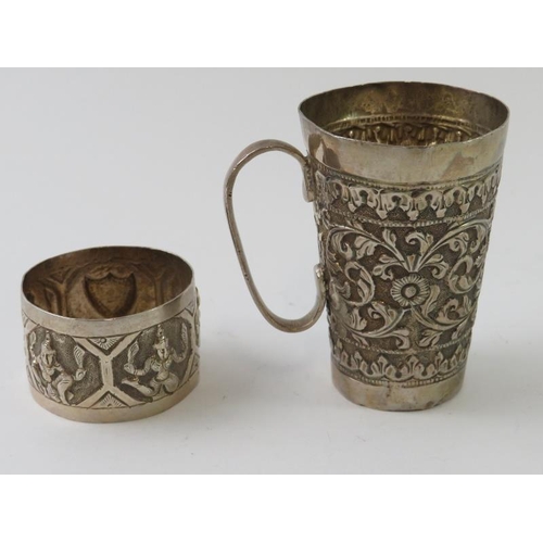 404 - An Eastern white metal mug with deep chased decoration marked T.90, and a similar napkin ring decora... 