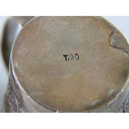 404 - An Eastern white metal mug with deep chased decoration marked T.90, and a similar napkin ring decora... 