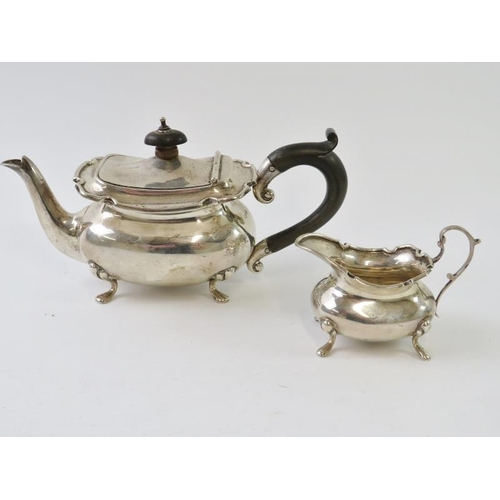 432 - An Edwardian silver bachelor tea pot and cream jug with pie crust rims and pad feet.  Tea pot with e... 