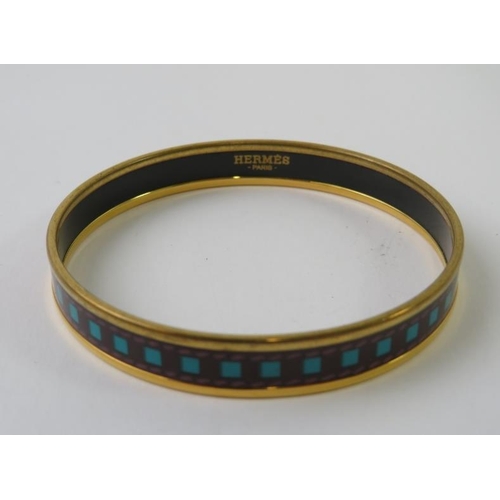 488 - HERMES: A  narrow belt printed enamel and yellow metal plated circular bangle 71mm diameter x 10mm h... 