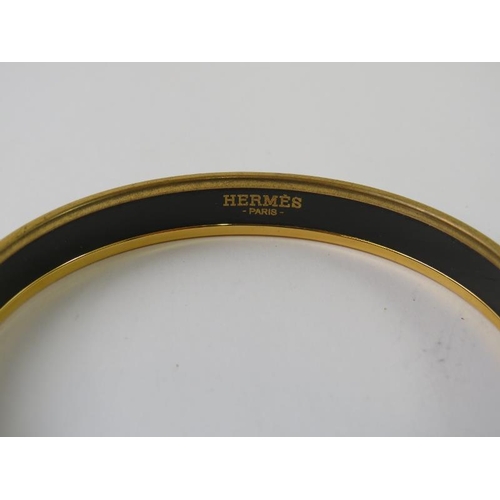 488 - HERMES: A  narrow belt printed enamel and yellow metal plated circular bangle 71mm diameter x 10mm h... 