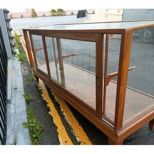 704 - An early 20th century light oak shop display counter, the twin sliding doors opening onto a fully gl... 