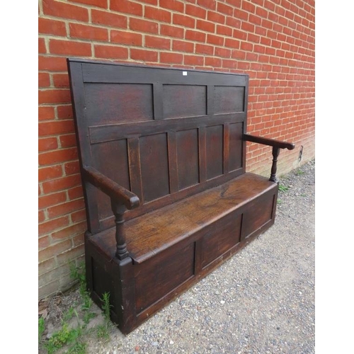 724 - An 18th century high back oak settle, the panelled back joined to a box settle base with internal st... 