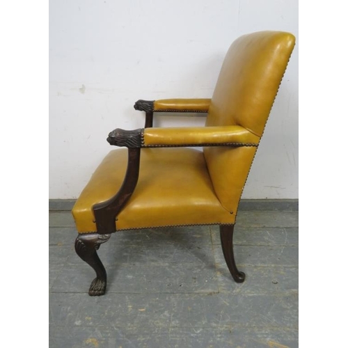 735 - An antique mahogany library chair in the 18th century taste, upholstered in mustard leather with bra... 