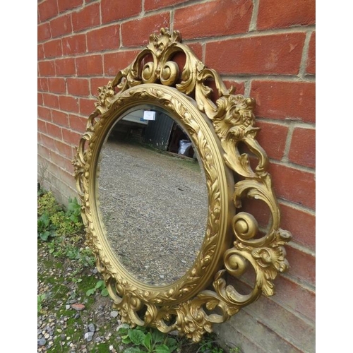 748 - A vintage circular bevelled wall mirror, within an ornate gilt gesso surround modelled as scrolling ... 