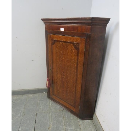 767 - A George III mahogany and oak hanging corner cupboard, inlaid and crossbanded, with marquetry spandr... 