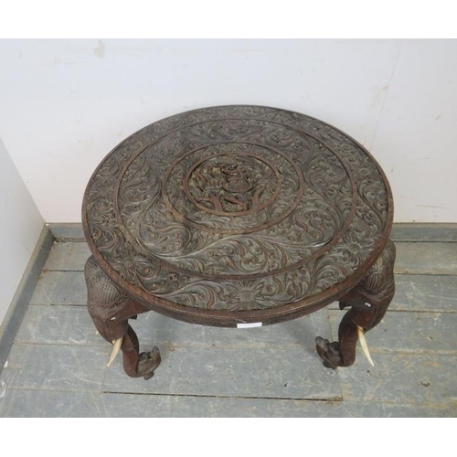 811 - An antique padouk elephant table, the circular top relief carved with foliate borders and central pa... 