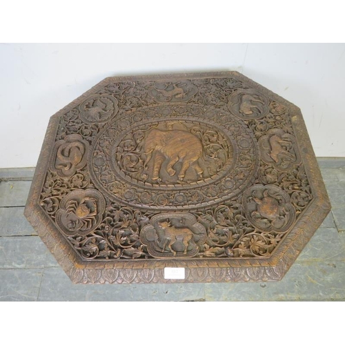 812 - An antique hardwood Indian table, the octagonal top carved in high relief with central elephant amid... 