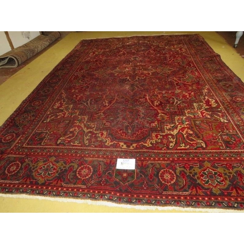 852 - A Northwest Persian Heriz carpet, central floral motif on deep red ground and wide borders.  290cm x... 