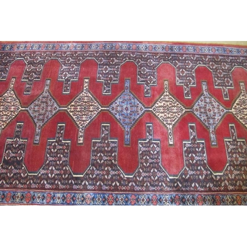 865 - A North West Persian Sennah runner with central repeat motif on red ground.  280cm x 90cm approx.
Co... 