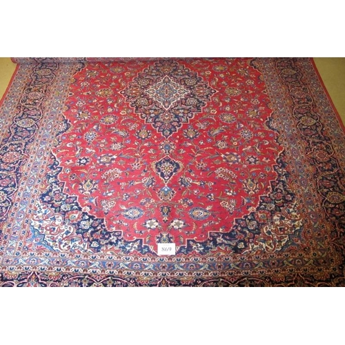 869 - A mid 20th Century Persian Kashan carpet.  Central motif, blue on red ground.  372cm x 283cm approx.... 