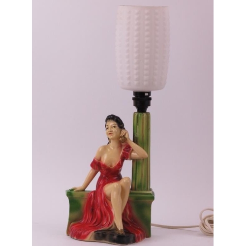 173 - A vintage cast plaster table lamp, circa 1950s. Modelled with a female in a long red dress on the te... 