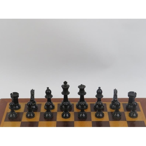 23 - An ebonised wood and sycamore chess set and parquetry inlaid gaming board.
The chess piece bases wei... 