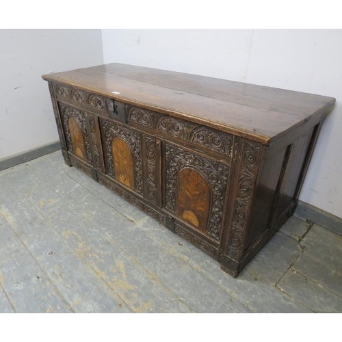 708 - An early 18th century oak panelled coffer, profusely carved with lunette frieze and arcaded front pa... 