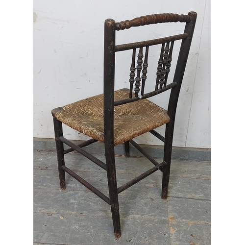 717 - A 19th century ebonised ‘Sussex’ chair, the backrest with turned spindles above a rush seat, on faux... 