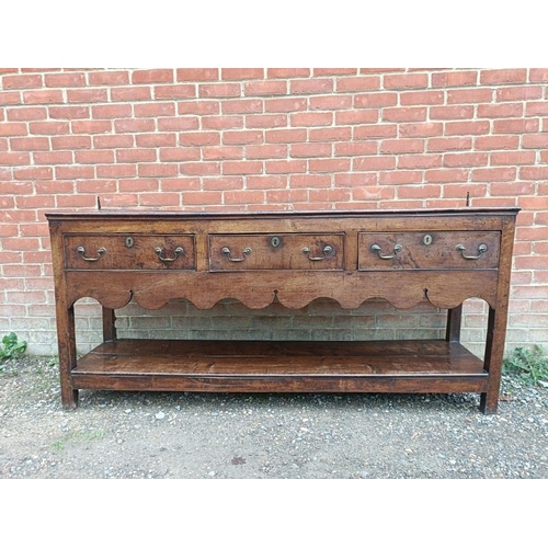 720 - An 18th century oak dresser base of good colour, housing three short drawers with brass swan-neck ha... 