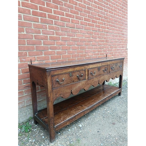 720 - An 18th century oak dresser base of good colour, housing three short drawers with brass swan-neck ha... 