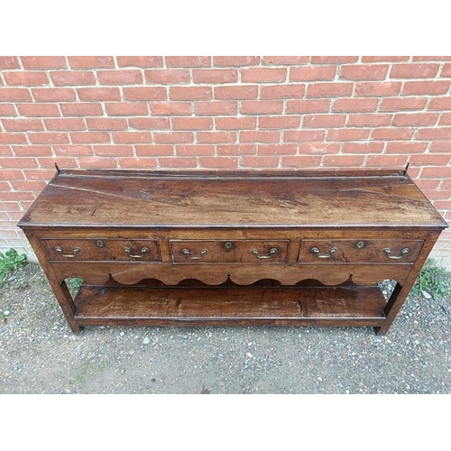 720 - An 18th century oak dresser base of good colour, housing three short drawers with brass swan-neck ha... 