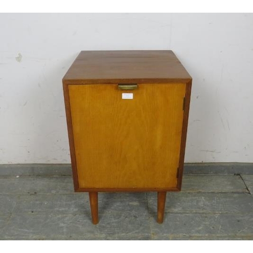 731 - A well-constructed mid-century solid teak side cabinet, the door with brass handle opening onto a lo... 