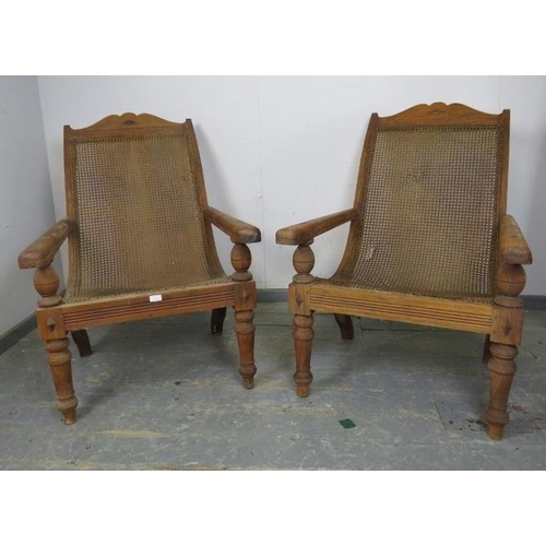 735 - A pair of early 20th century teak plantation chairs, having bergère seats and swing-out interlocking... 