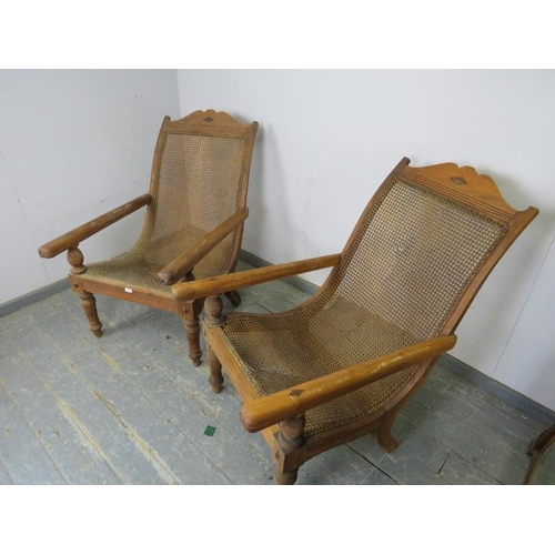 735 - A pair of early 20th century teak plantation chairs, having bergère seats and swing-out interlocking... 