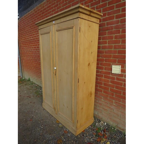 742 - A stripped antique pine double wardrobe, the panelled doors opening onto a hanging rail and turned c... 