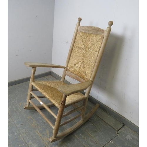 749 - A 19th century light oak and beech rocking chair, with ball finials above a rush seat and backrest, ... 