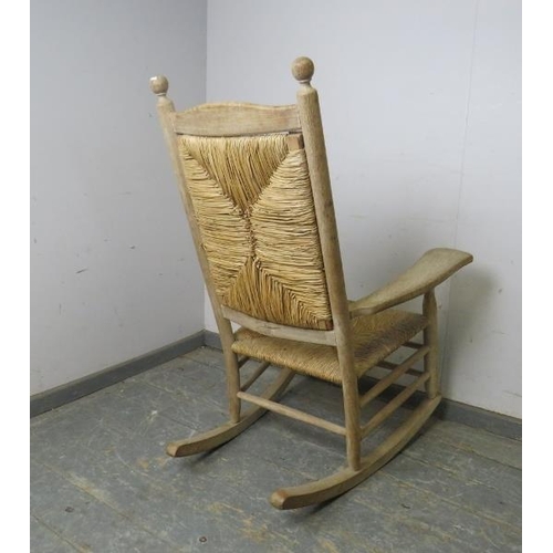 749 - A 19th century light oak and beech rocking chair, with ball finials above a rush seat and backrest, ... 