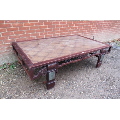 751 - A large antique Chinese bed, converted into a statement coffee table, the rattan top above a carved ... 