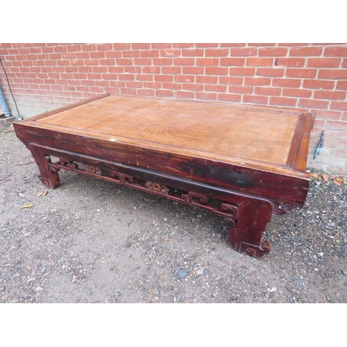 752 - A large antique Chinese bed, converted into a statement coffee table, the rattan top above a carved ... 