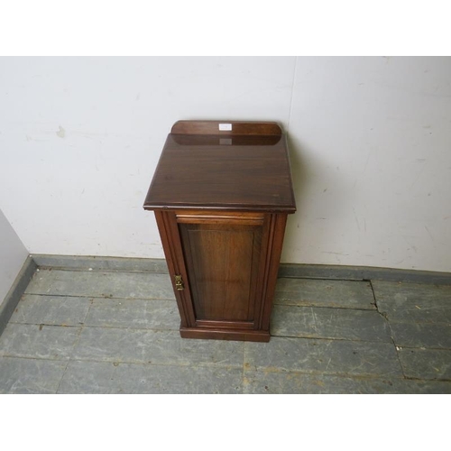 760 - An Edwardian mahogany bedside cabinet, the panelled door opening onto a loose shelf, on a plinth bas... 